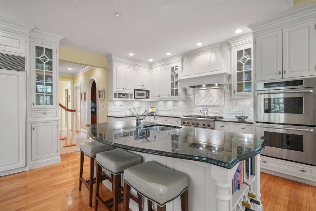 1 Old Farm Road Wellesley, MA 02481 - Photo 21 of 41 a kitchen with stainless steel appliances granite countertop a stove top oven a refrigerator a sink and a dining table with wooden floor