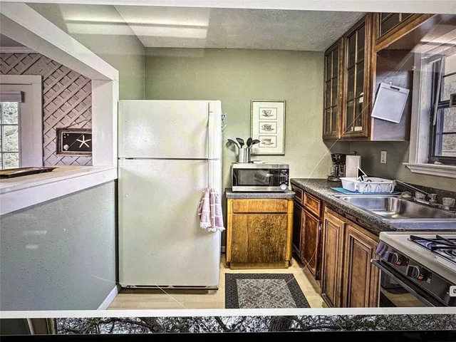 a kitchen with stainless steel appliances granite countertop a refrigerator a stove and a sink with wooden cabinets