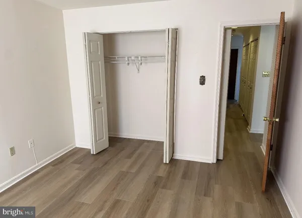 a view of an empty room with wooden floor and a bathroom