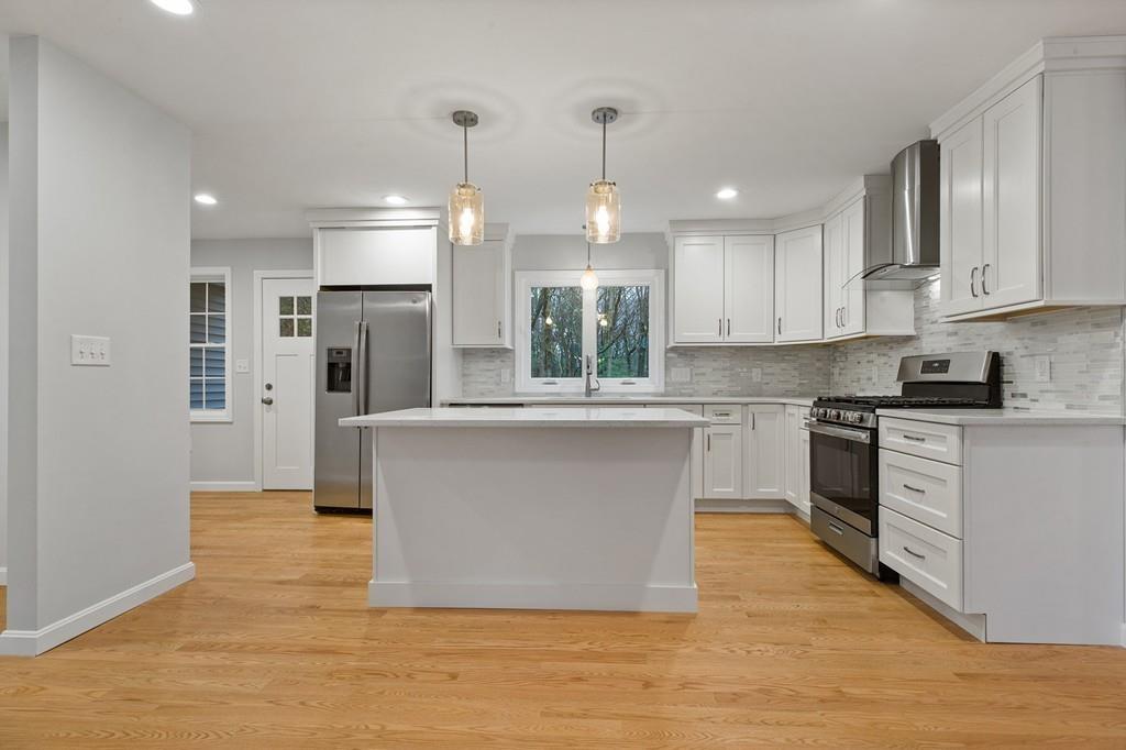 6 Sheffield Road Framingham, MA 01701 - Photo 8 of 32 a large kitchen with stainless steel appliances kitchen island a large counter top a stove a refrigerator cabinets and living room view