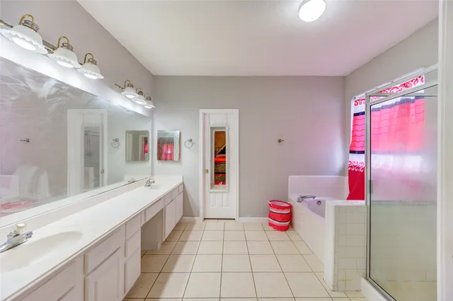 a bathroom with a tub sink vanity and granite countertops
