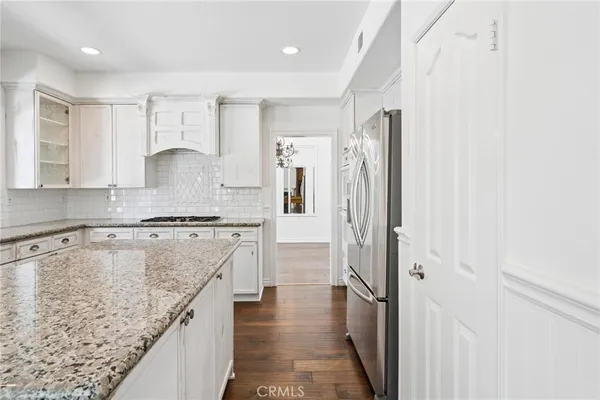 a kitchen with granite countertop a sink stainless steel appliances and white cabinets