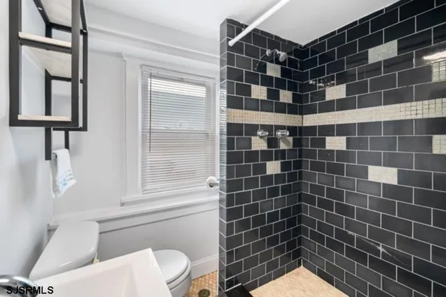 a bathroom with a toilet a sink a window and mirror