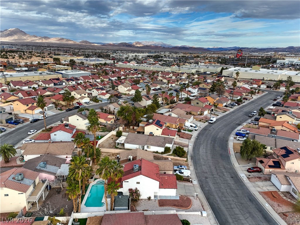 581 Carleton Drive Henderson, NV 89014 - Photo 32 of 37 An aerial perspective reveals a vibrant neighborhood nestled against distant mountains under an expansive sky.