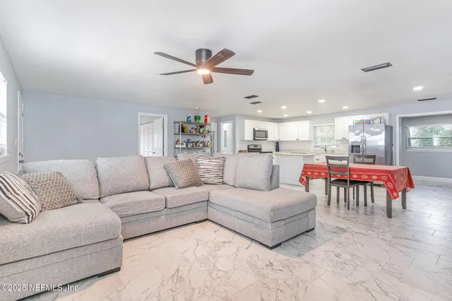 a living room with furniture and a dining table with kitchen view