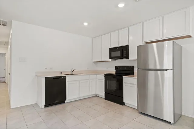 a kitchen with granite countertop a refrigerator and a stove top oven