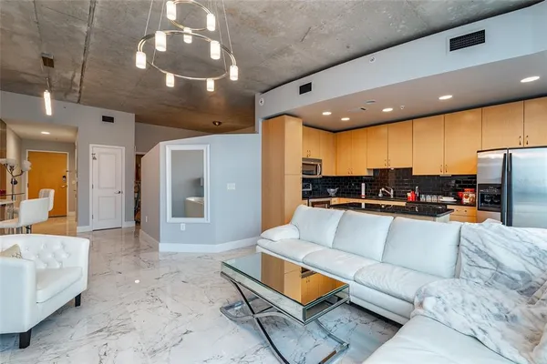 a living room with furniture kitchen view and a chandelier