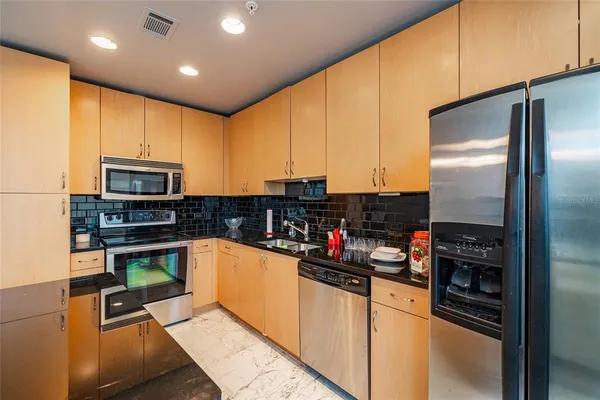 a kitchen with stainless steel appliances kitchen island granite countertop a refrigerator and a stove top oven
