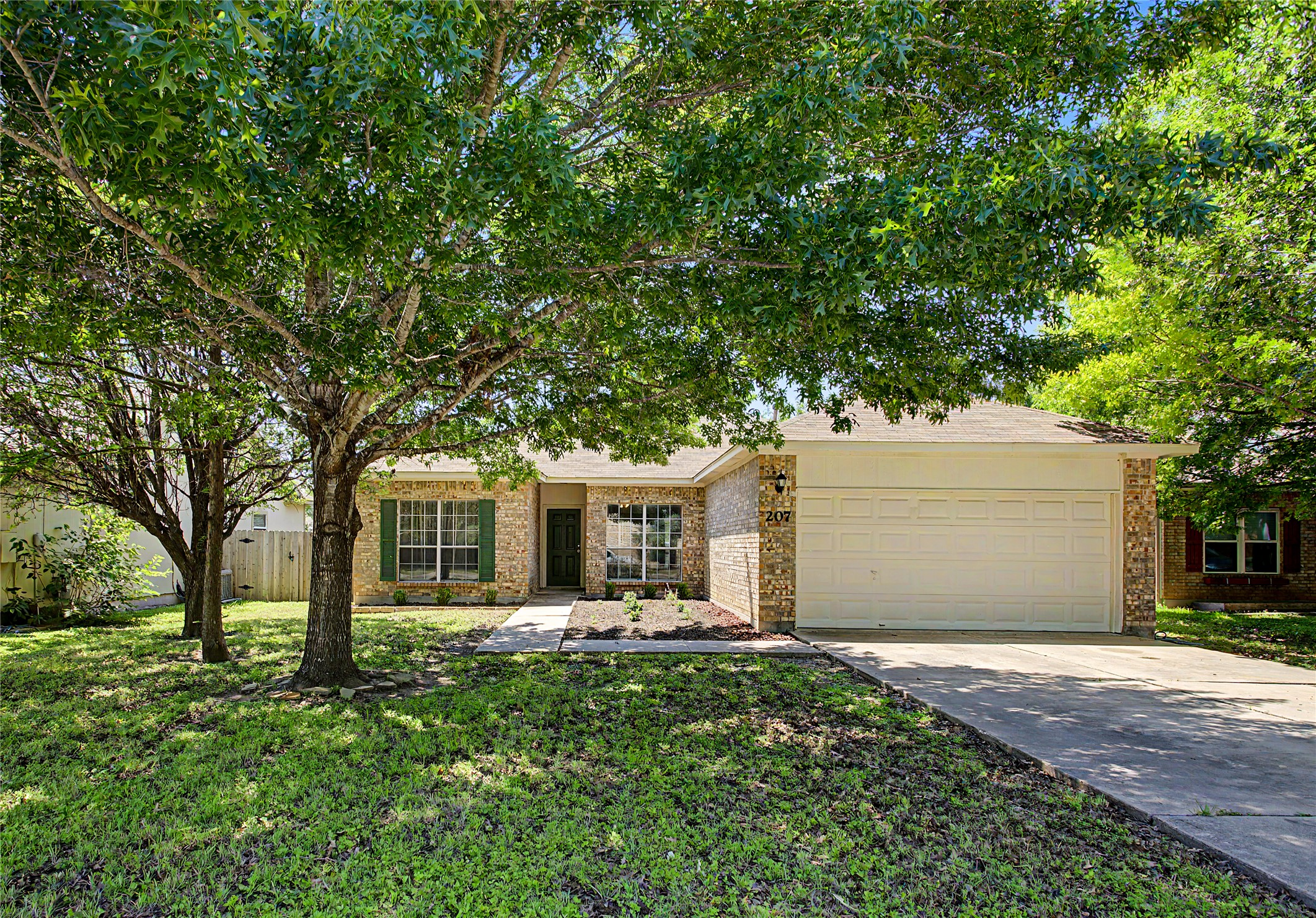 207 Kates Way Hutto, TX 78634 - Photo 12 of 24 Single-story residence featuring a brick facade, attached two-car garage, and a concrete driveway
