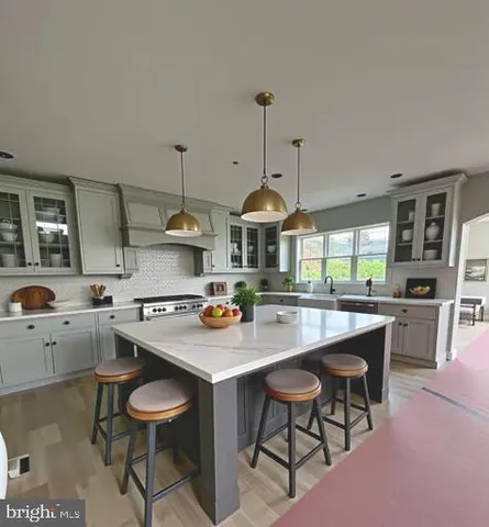 a kitchen with a stove a sink a kitchen island with chairs and wooden cabinets