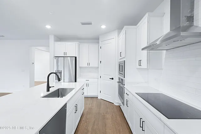 a kitchen with white cabinets a sink and stainless steel appliances