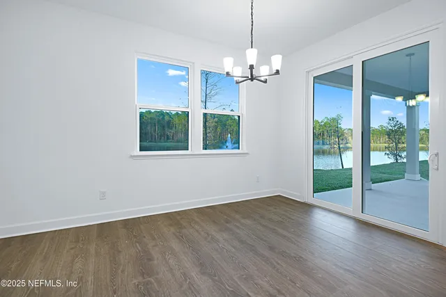 an empty room with wooden floor a chandelier and windows