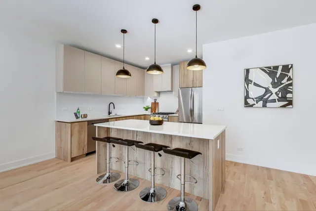 a kitchen with stainless steel appliances kitchen island a table chairs in it and wooden floors