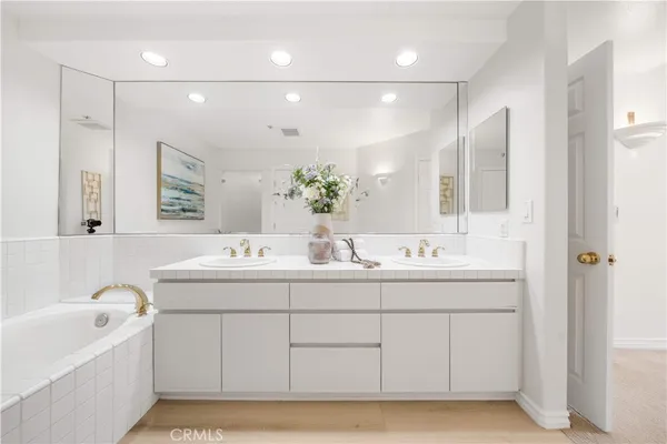 a bathroom with a double vanity sink mirror and bathtub