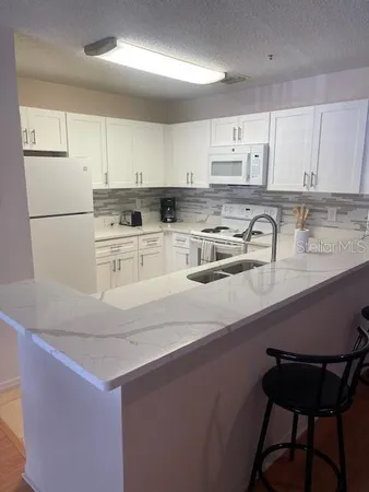 a kitchen with a sink a stove a refrigerator and white cabinets