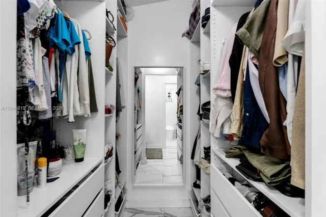 a view of walk in closet with clothes and shoes