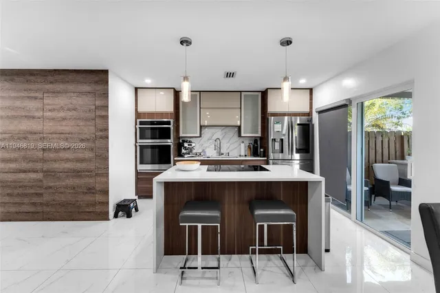 a view of kitchen with kitchen island stainless steel appliances a sink and chairs