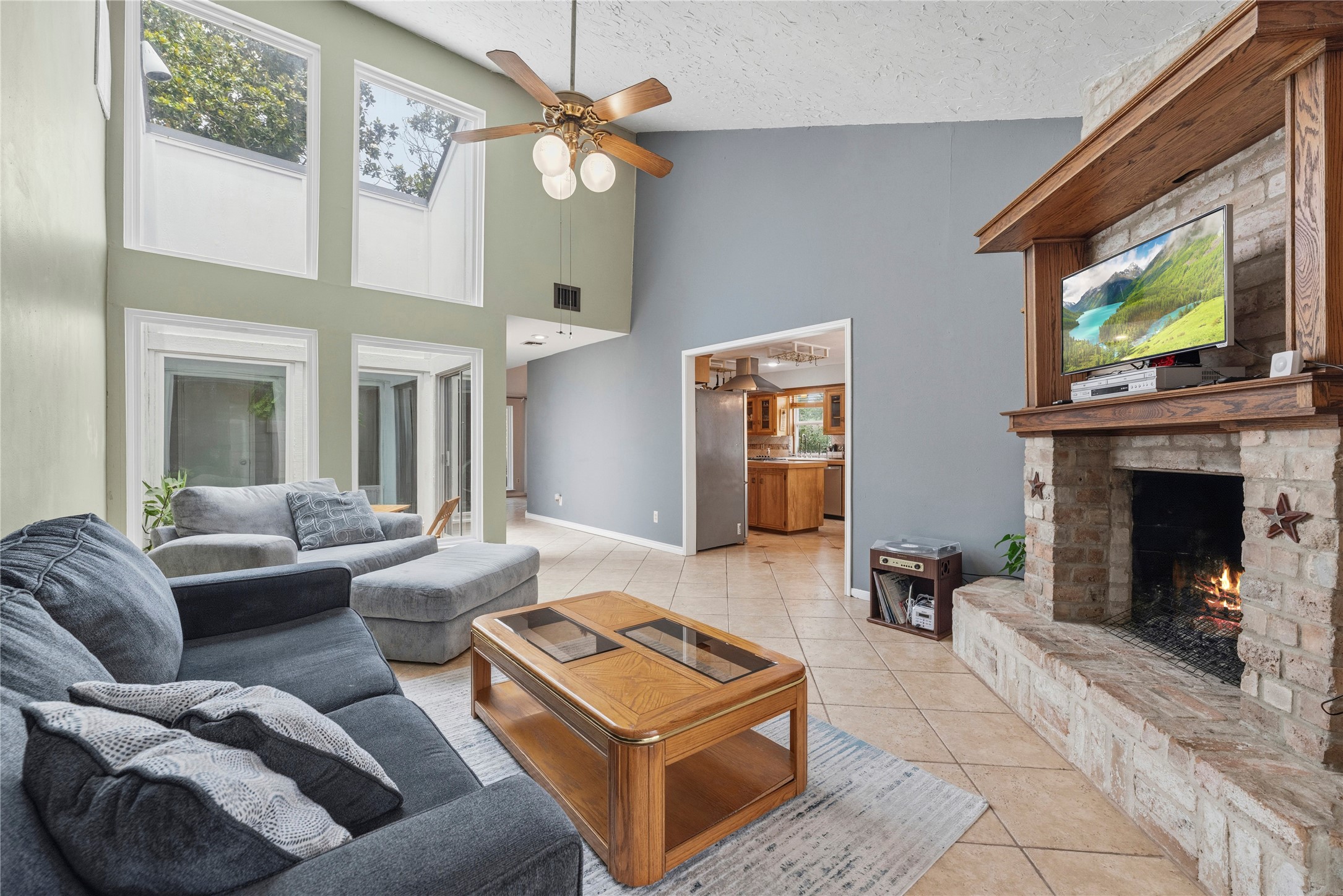 14203 Wickersham Lane Houston, TX 77077 - Photo 8 of 25 Alternative view of the family room highlighting the soaring ceiling height, built-in upper transom windows drawing in maximum daylight, and the wide entry threshold connecting directly to the kitchen area.