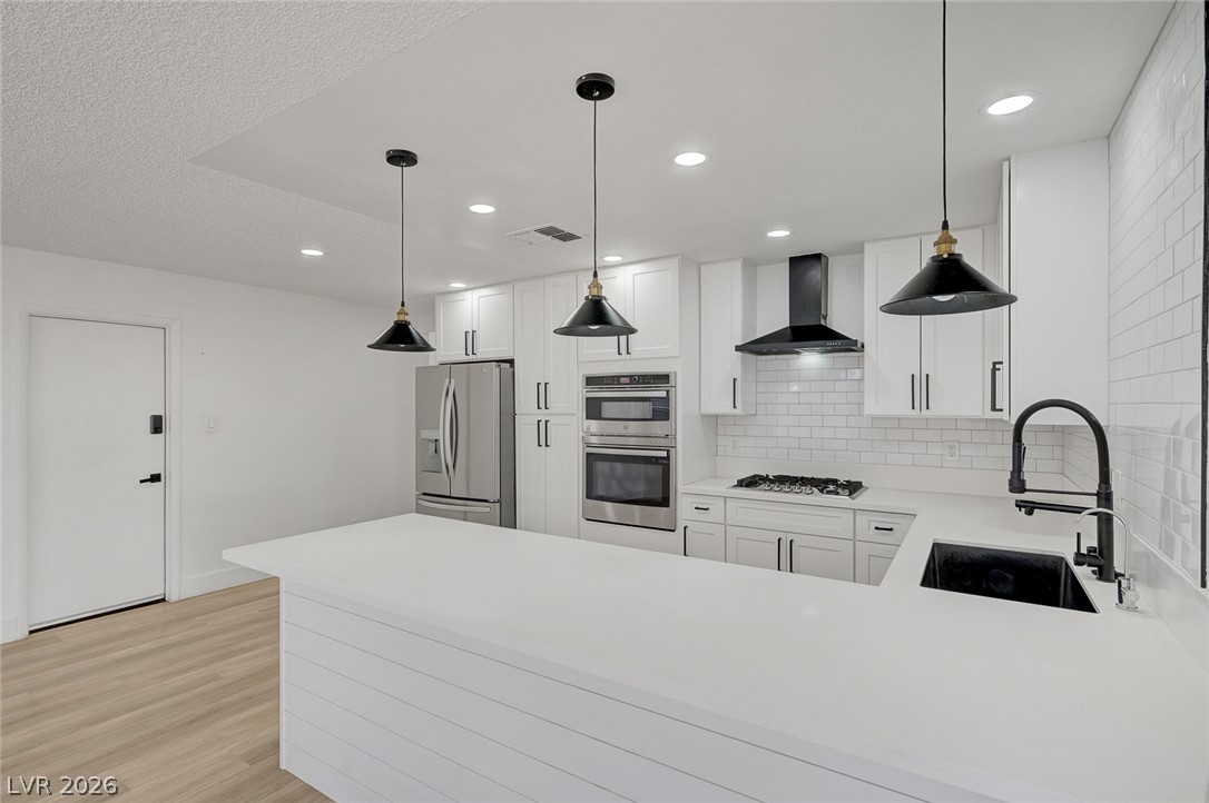 4840 Summerhill Road Las Vegas, NV 89121 - Photo 16 of 56 A pristine white kitchen features a large island and contemporary pendant lighting, complementing sleek appliances.