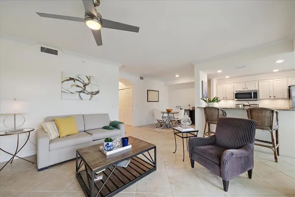 a living room with furniture kitchen view and a chandelier