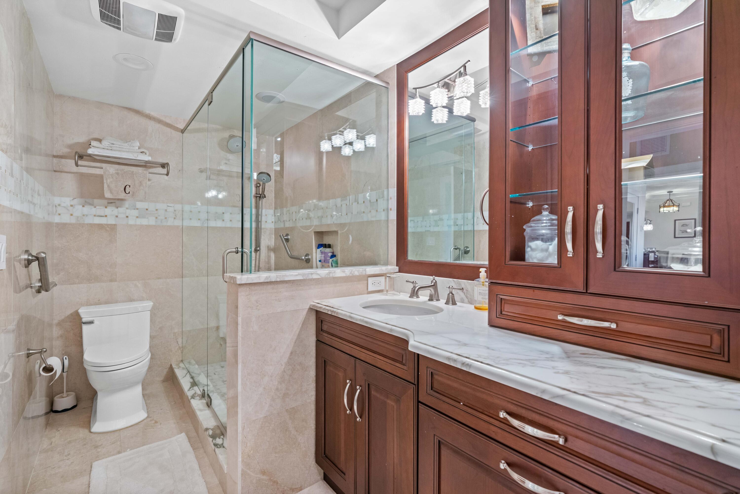 2000 Florida A1A, Unit 406 Jupiter, FL 33477 - Photo 19 of 40 a bathroom with a granite countertop sink a toilet a large mirror and shower