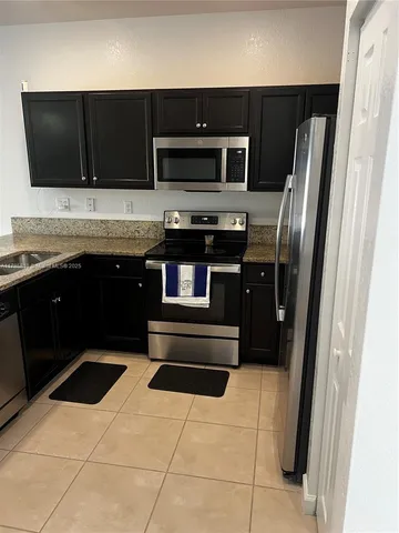 a kitchen with a refrigerator and a stove top oven