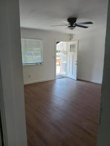 an empty room with wooden floor cabinet and windows