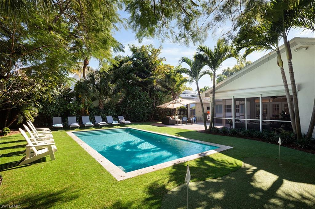 339 4th Avenue North Naples, FL 34102 - Photo 12 of 48 a view of a house with swimming pool and yard with green space