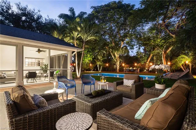 a view of a patio with couches chairs and a fire pit with large trees
