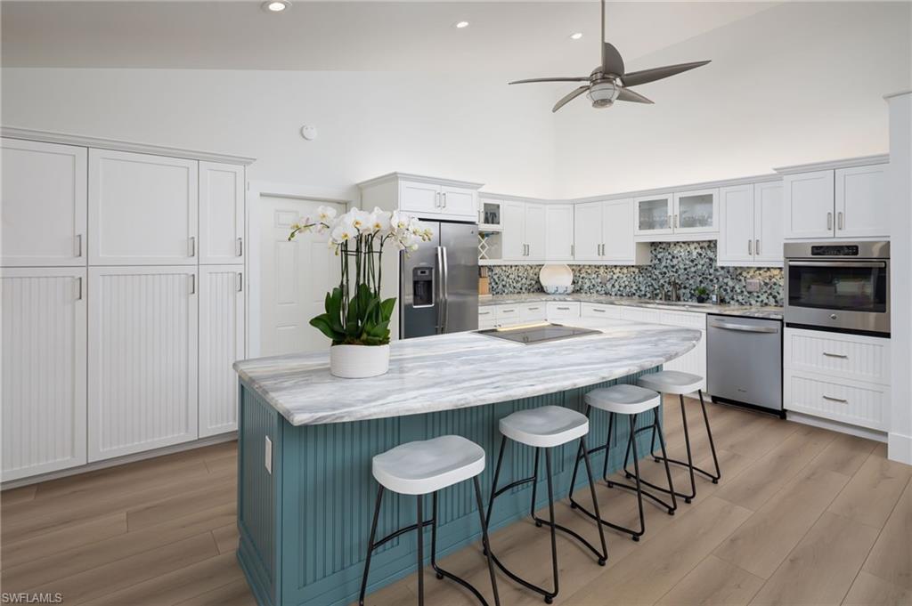339 4th Avenue North Naples, FL 34102 - Photo 24 of 48 a kitchen with stainless steel appliances kitchen island a wooden floor and white cabinets