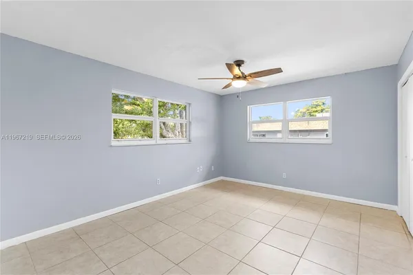 an empty room with windows and ceiling fan
