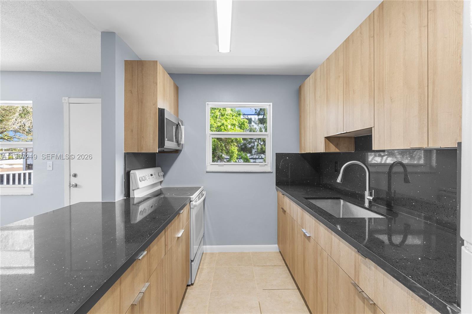 3265 Griffin Road, Unit 206 Dania Beach, FL 33312 - Photo 7 of 15 a kitchen with stainless steel appliances granite countertop a sink a stove and a wooden floors