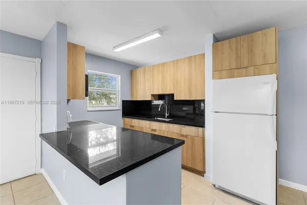 a kitchen with kitchen island a sink a stove a refrigerator a washer and dryer