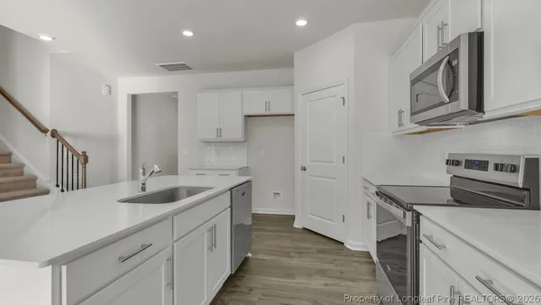 a kitchen with stainless steel appliances granite countertop a sink and dishwasher a stove top oven with wooden floor