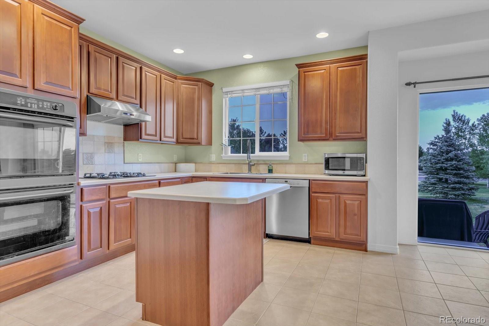 4786 Rabbit Mountain Road Broomfield, CO 80020 - Photo 9 of 41 a kitchen with kitchen island granite countertop a sink counter top space appliances and cabinets