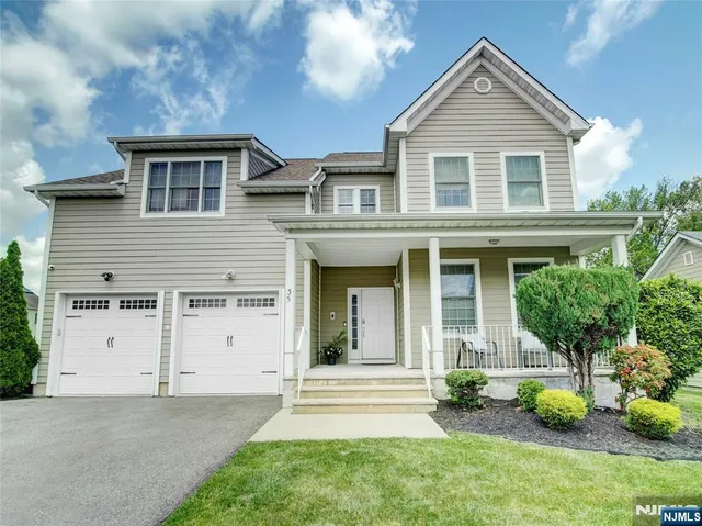 a view of a brick house with a yard plants and a large tree