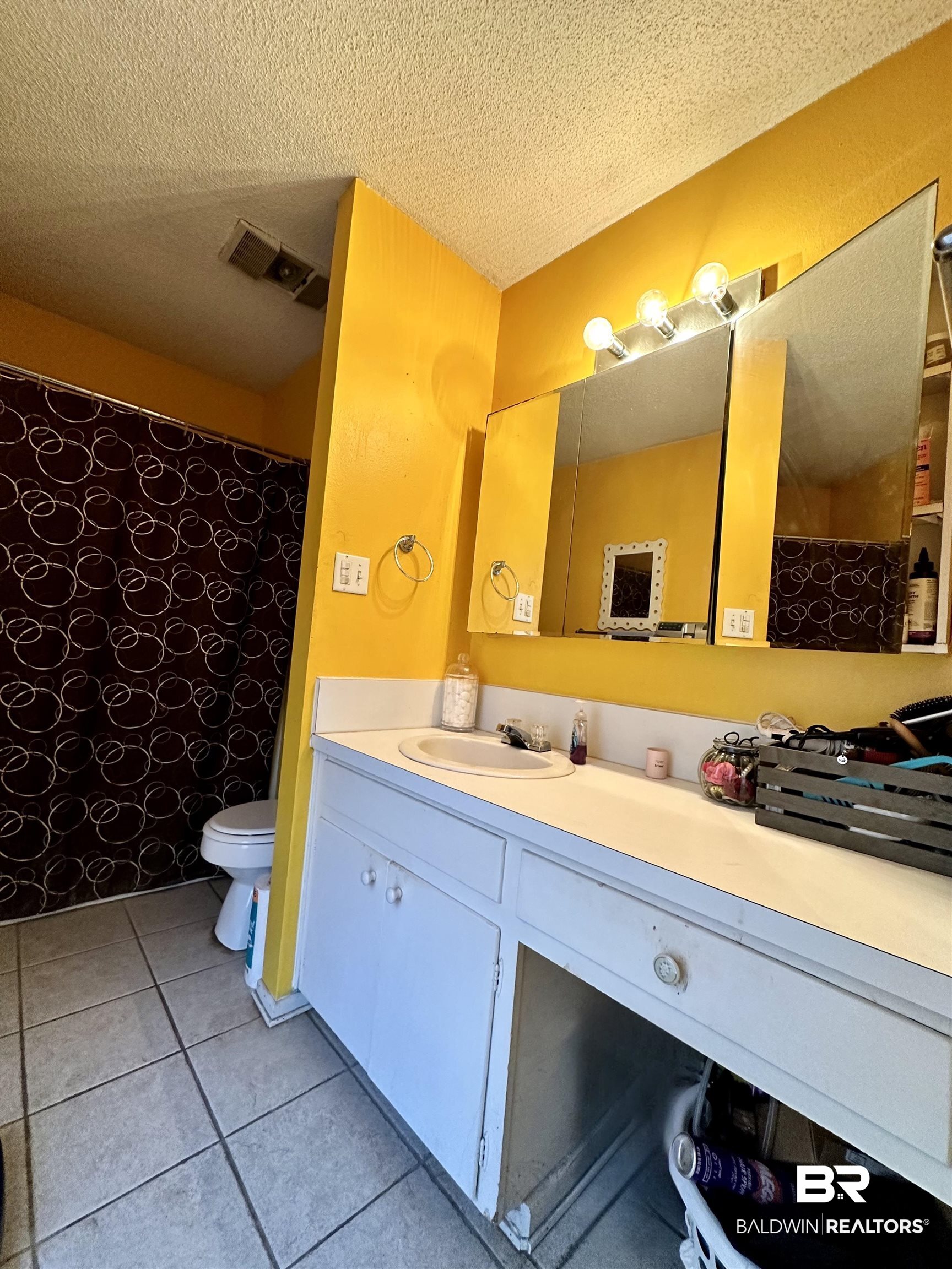 2593 Foshee Road Brewton, AL 36426 - Photo 8 of 15 Bathroom featuring a textured ceiling, a shower with shower curtain, toilet, vanity, and tile patterned flooring