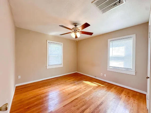 a view of an empty room with window and wooden floor