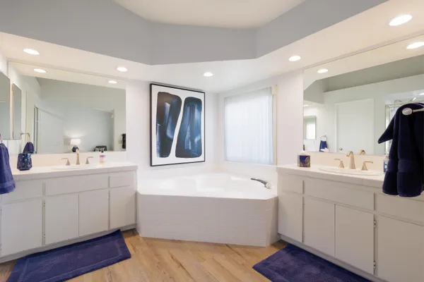 a bathroom with a bathtub a mirror a double vanity sinks and vanity