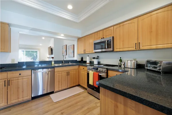a kitchen with stainless steel appliances granite countertop a stove a sink dishwasher and a microwave oven with wooden floor