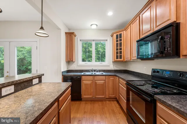 a kitchen with stainless steel appliances granite countertop hardwood floor sink stove and granite counter top