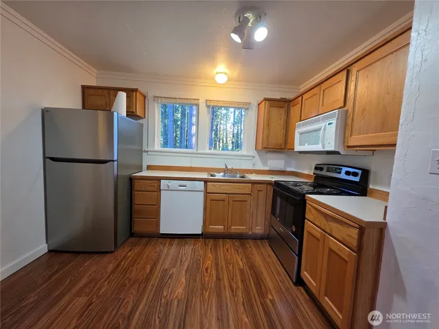 a kitchen with granite countertop a refrigerator stove top oven and sink