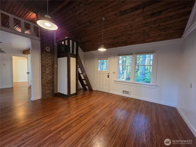 a view of empty room with wooden floor and windows