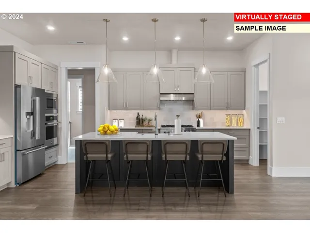 a kitchen with stainless steel appliances a dining table chairs refrigerator and microwave