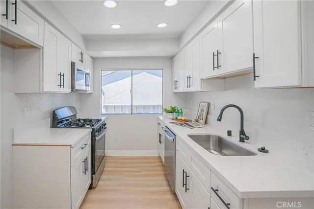 a kitchen with stainless steel appliances granite countertop a sink stove refrigerator and cabinets