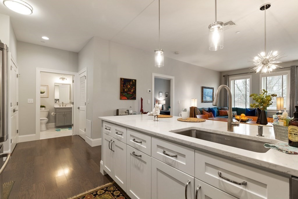 8 Sanborn Street, Unit 1009 Reading, MA 01867 - Photo 11 of 30 a large kitchen with kitchen island a stove a sink a refrigerator and a granite counter tops with white cabinets
