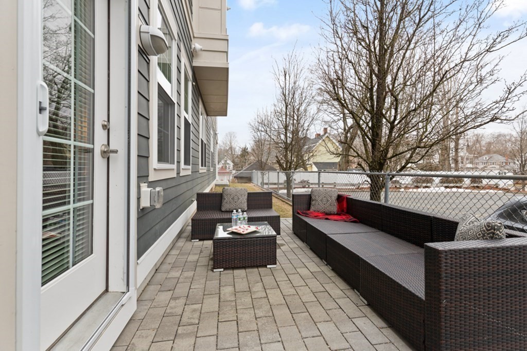 8 Sanborn Street, Unit 1009 Reading, MA 01867 - Photo 25 of 30 a view of a patio with couches and table and chairs with wooden floor and fence