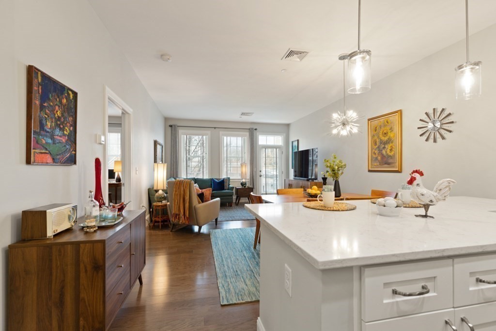 8 Sanborn Street, Unit 1009 Reading, MA 01867 - Photo 5 of 30 a view of a dining room and livingroom with furniture wooden floor a rug a flat screen tv a rug and a chandelier