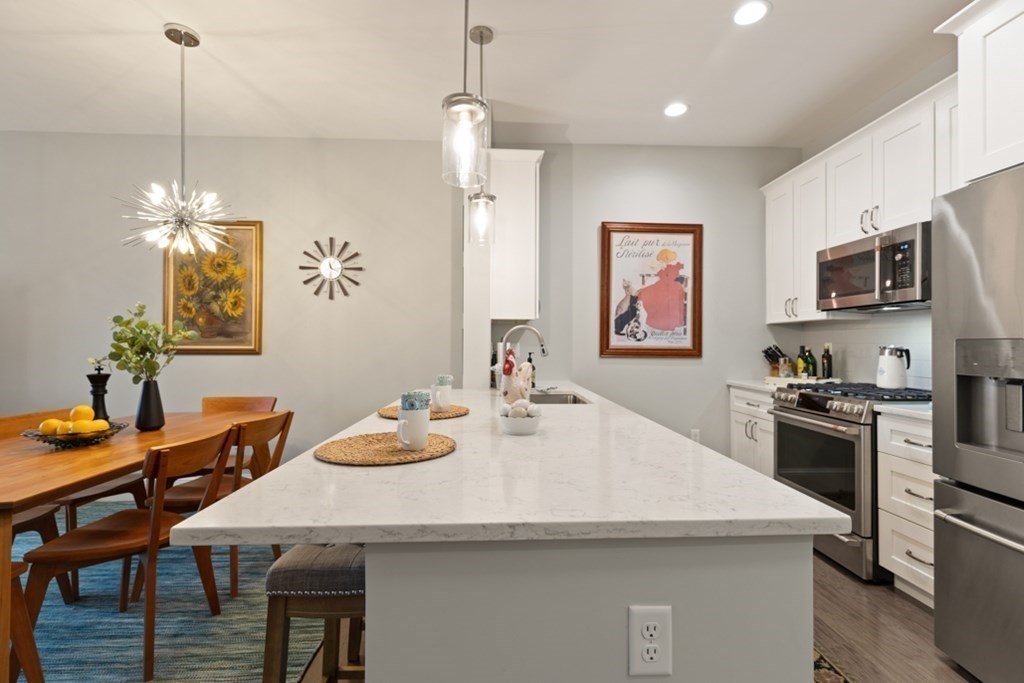 8 Sanborn Street, Unit 1009 Reading, MA 01867 - Photo 8 of 30 a kitchen with stainless steel appliances granite countertop a sink a stove a dining table and chairs