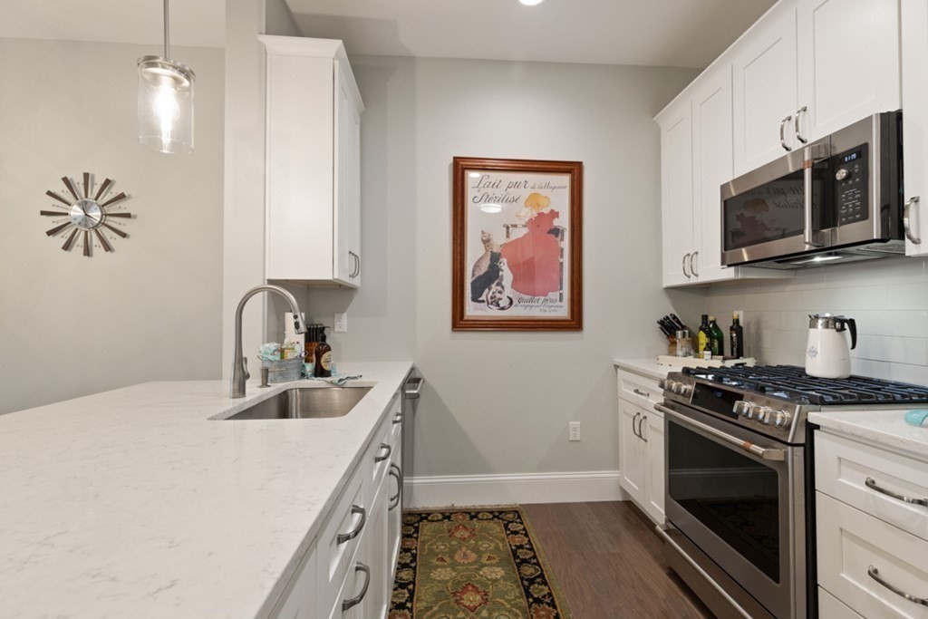 8 Sanborn Street, Unit 1009 Reading, MA 01867 - Photo 9 of 30 a kitchen with stainless steel appliances a stove a sink and a microwave
